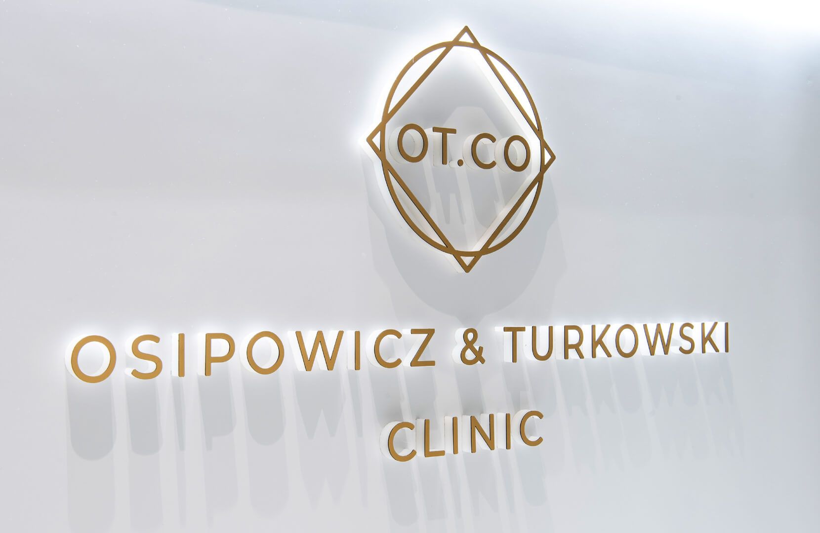 Lettres spatiales dans l'espace d'accueil de la clinique OT.CO - Lettres spatiales dorées avec logo dans la zone de réception de la clinique OT.CO